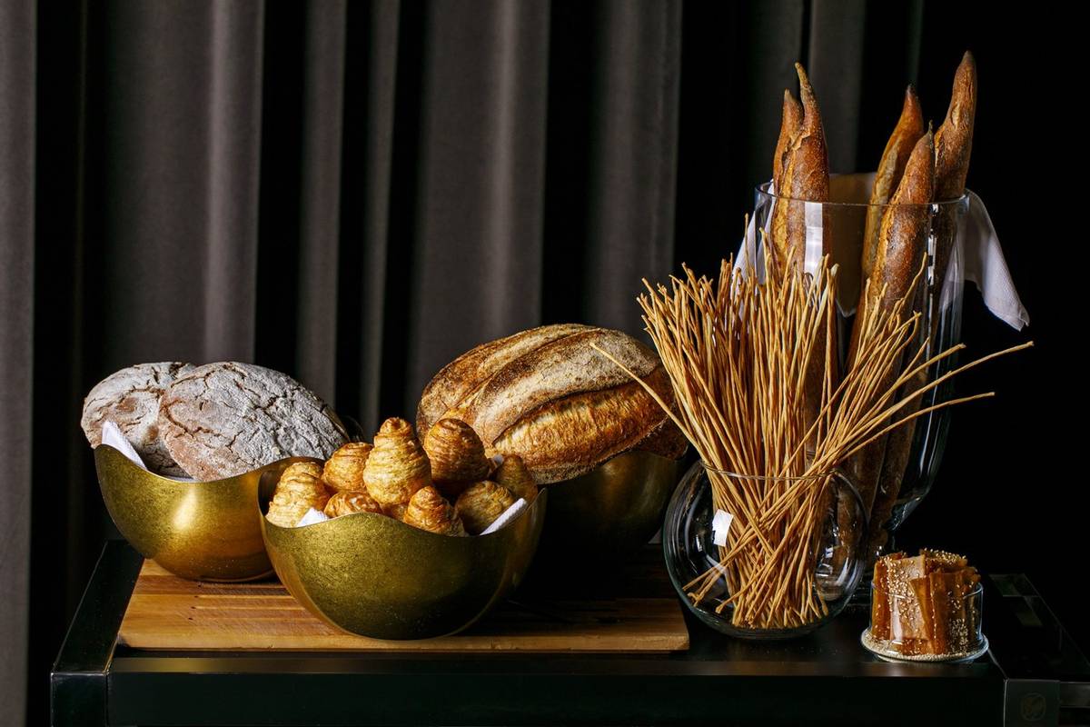 Il carrello del pane di INEO: pagnotte su un fondale scuro, con ciotole dorate.